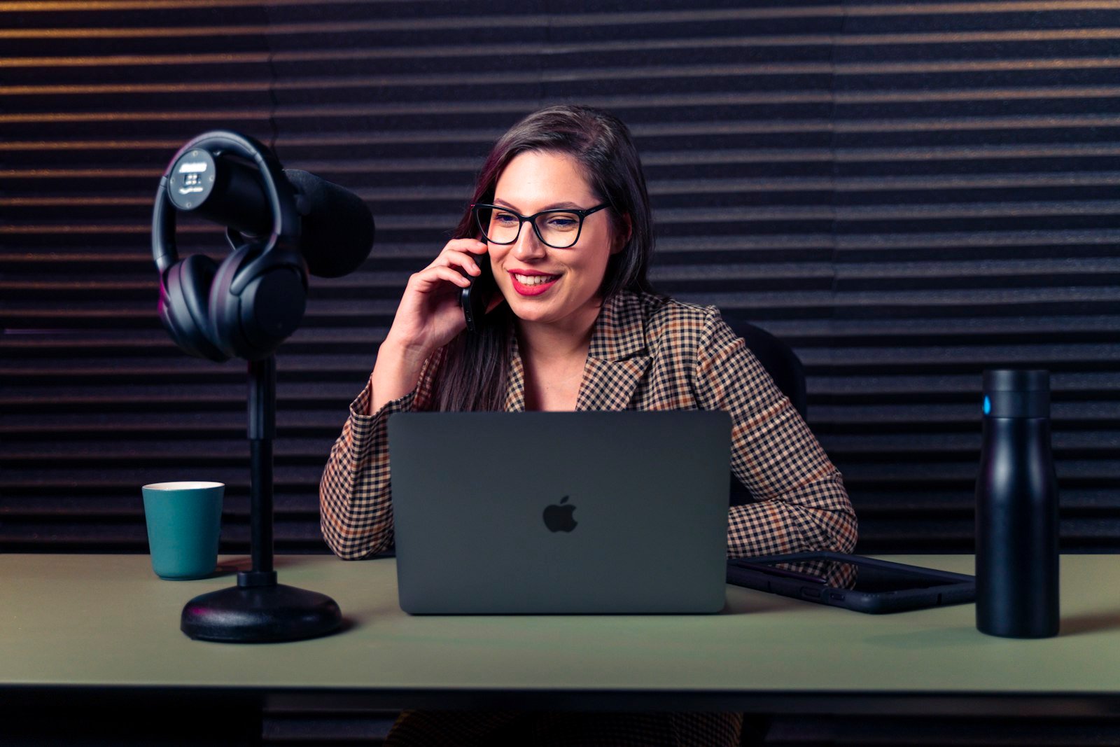 Woman at a desk using a laptop and external microphone for a call